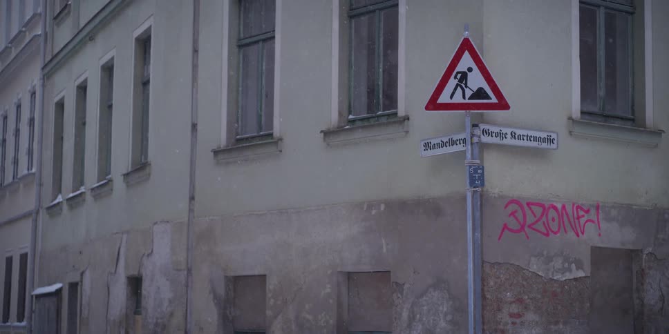 Street signs in front of a neighborhood apartment building as snow falls