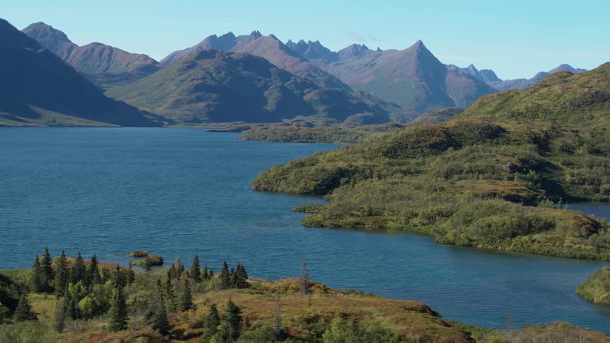 Lake surrounded by hills and mountains under clear sky