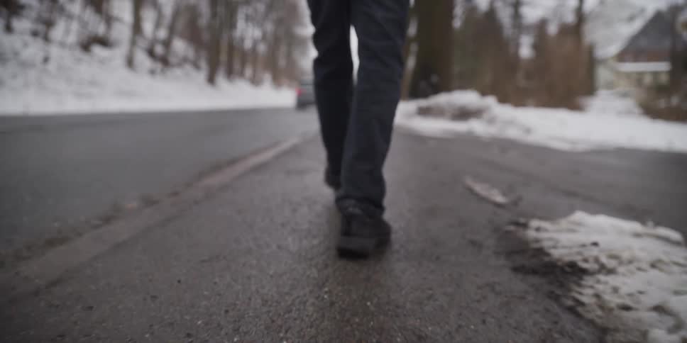 A man walking down the side of a road on a snowy day