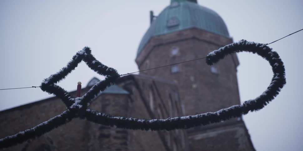 A snowdusted decorative garland hangs in the foreground while a domed church tower looms softly blurred in the background