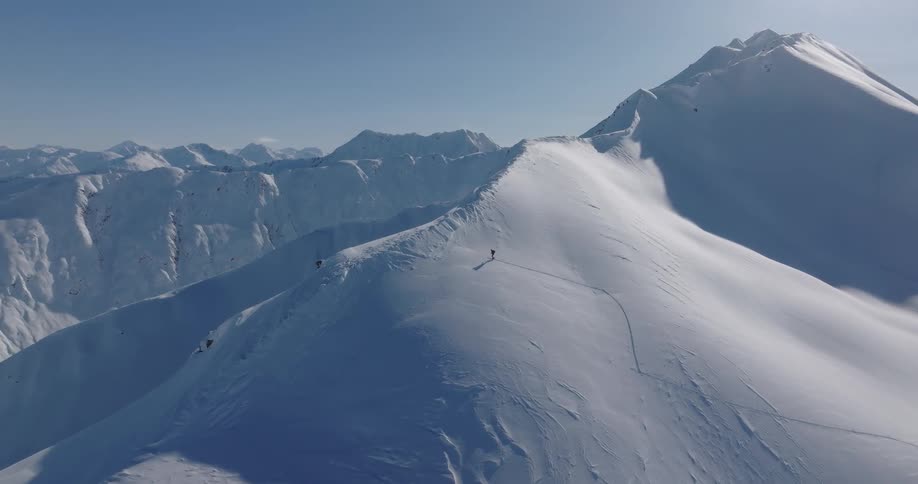 Hiker climbing up a snow covered mountain slope