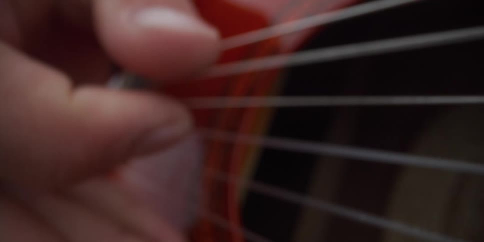 A close up of a man strumming a guitar