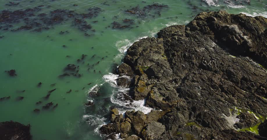 Ascending aerial shot over the turquoise waters and rugged rock formations of a scenic coastline