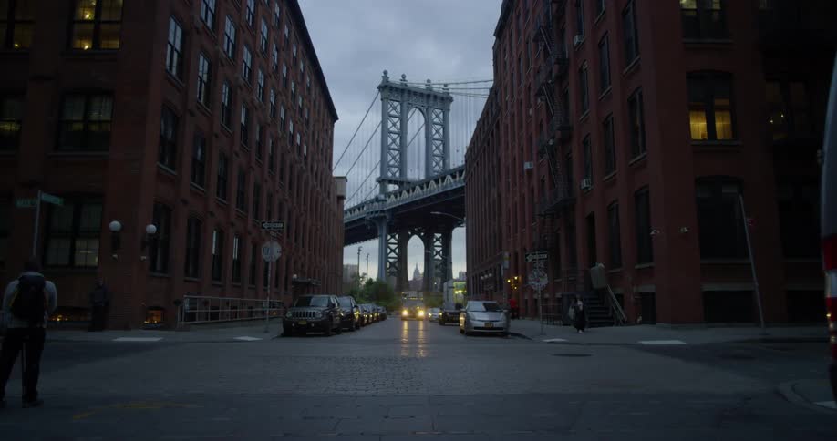 Cars parked on a busy city street with a bridge in the background