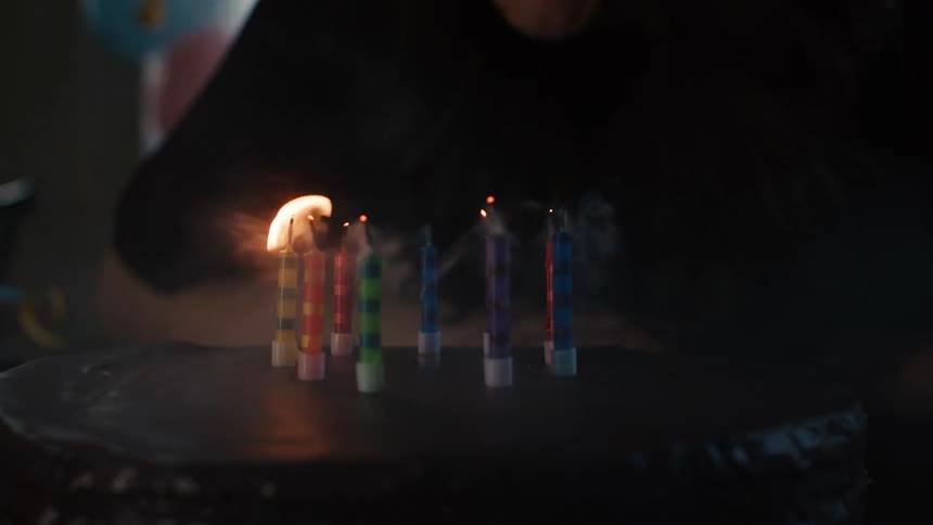 Slow motion close up shot of a person blowing out colorful candles on a birthday cake
