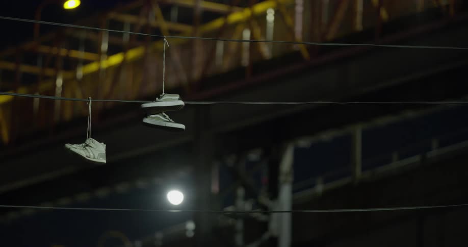 Shoes hang from telephone wires at night