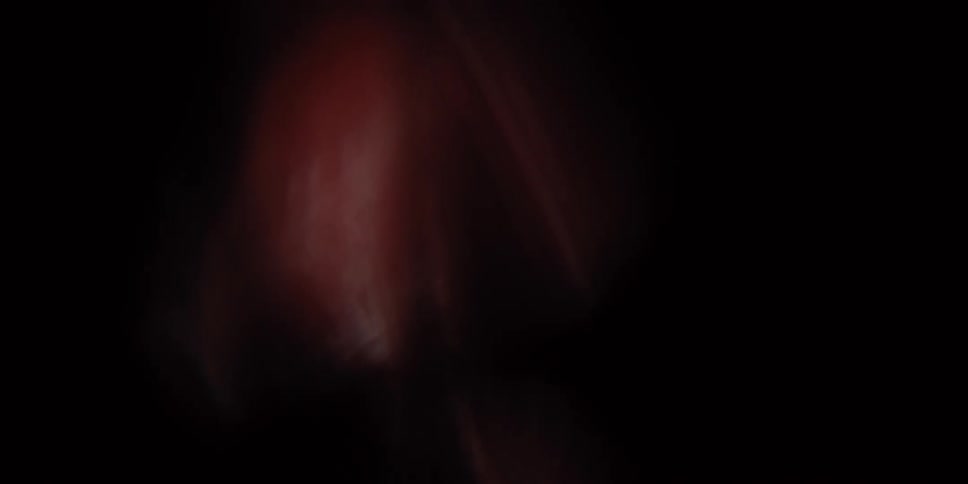 An abstract macro shot of a textured red object slowly appearing and shifting in the darkness