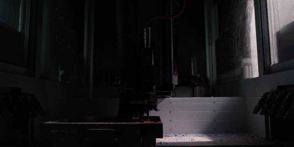 A sophisticated CNC milling machine operates in a darkened industrial setting, precisely cutting and shaping a workpiece