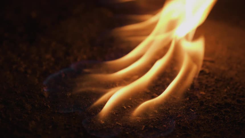 A flame ignites and burns on the ground