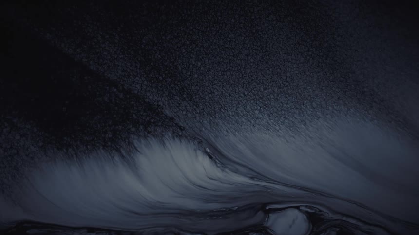 A dark and moody abstract background where black and white inks slowly flow and mix together