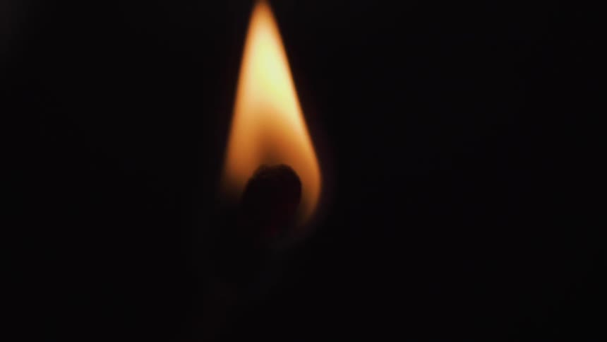 A flame is burning in the dark