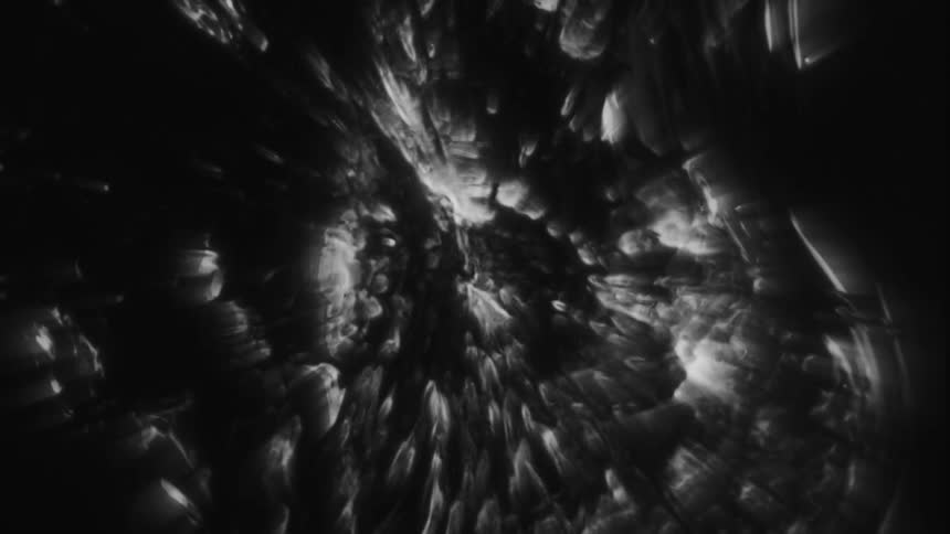 Dark, amorphous shapes slowly pulse and shift in a black and white abstract animation