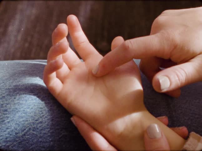 A close-up of a mother's hand gently tracing the lines on her child's palm in a tender moment