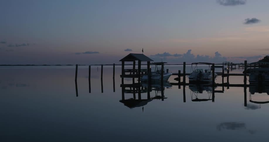 Boats are parked at a dock at sunset