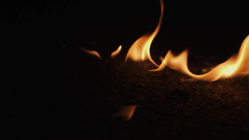 Flames licking off a burning object in a dark room