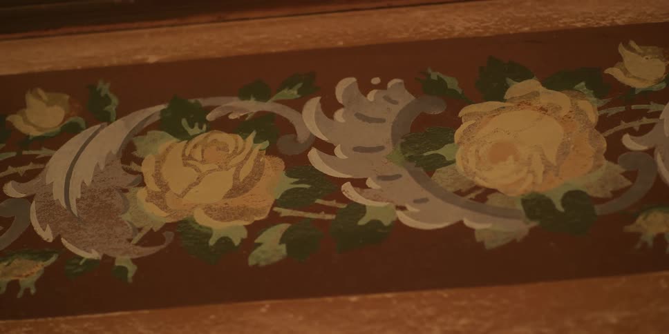 A close-up static shot of a vintage, hand-painted floral border featuring yellow roses and ornate scrolls