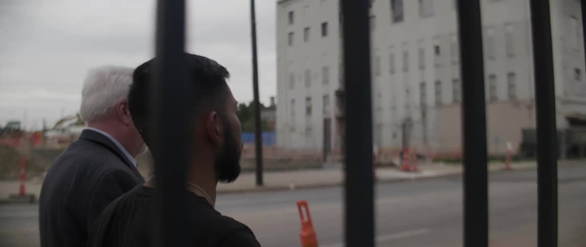 Two men walk down a city sidewalk