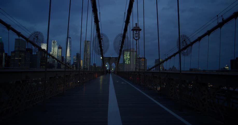 Cars drive below on this bridge towards a city at dawn