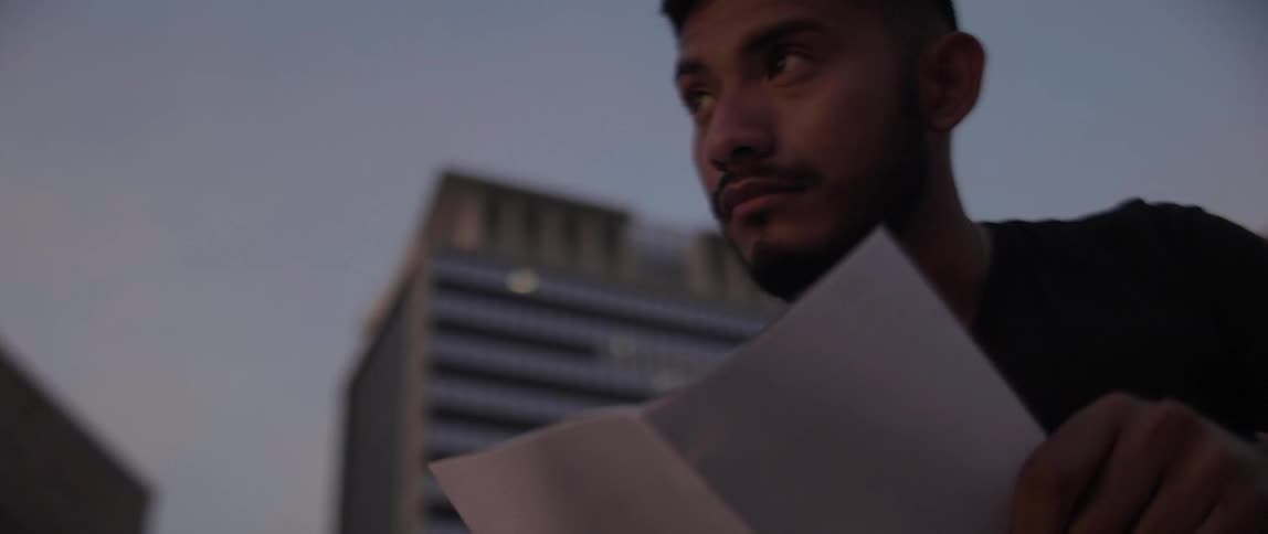 Man sits outside looking at a sheet of paper