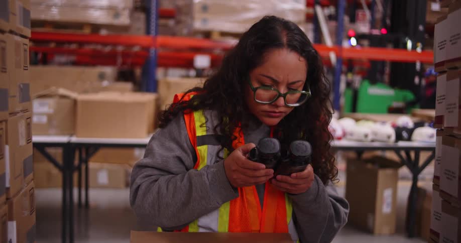 A focused warehouse employee performs a quality control check, carefully inspecting bottles before packing them