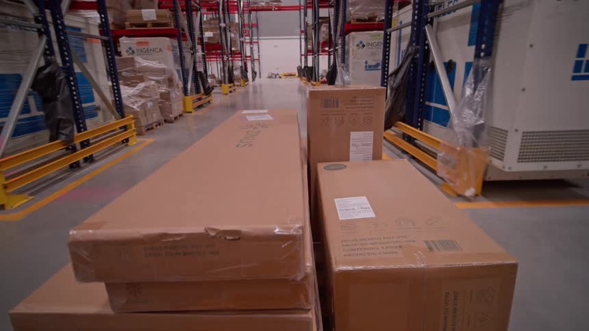 A dynamic time-lapse captures the bustling activity of a large industrial warehouse, with forklifts and workers moving inventory among towering shelves