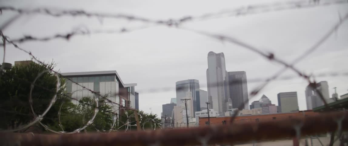 Tall city buildings seen through barbed wire