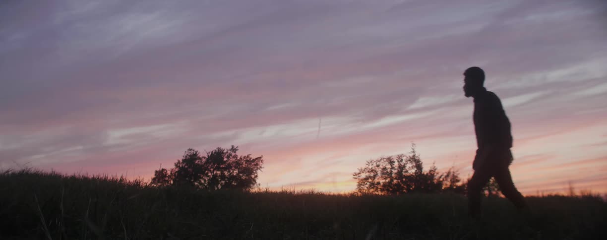 Man walking outside in field at sunset