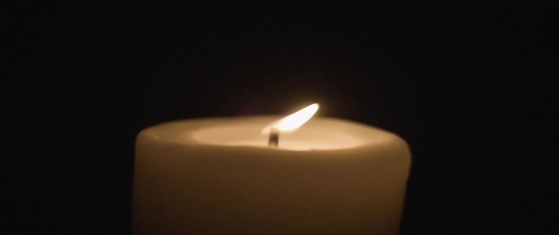 A candle flickers and burns