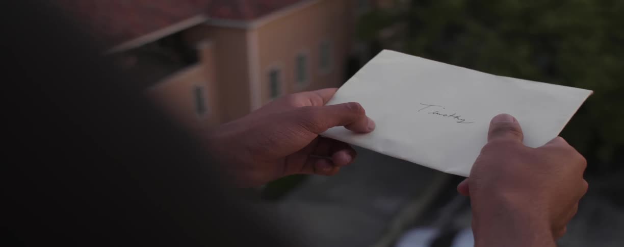 A man holds an envelope with a name written on it