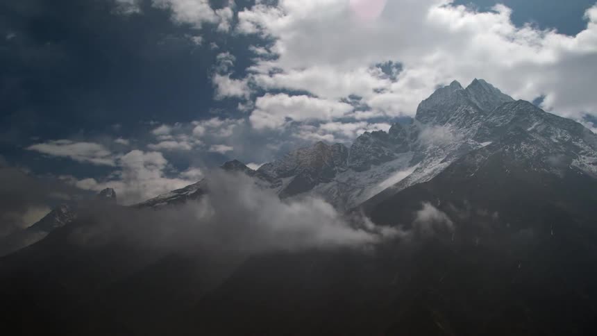 Time lapse view of clouds rolling over snow tipped mountains