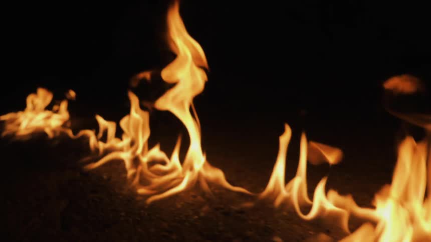 A fire burns on the ground at night