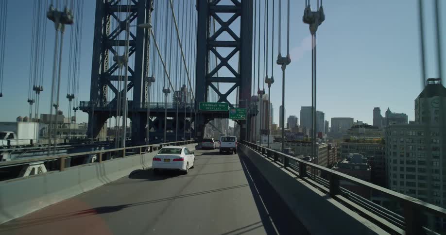 Cars drive across the bridge towards the city
