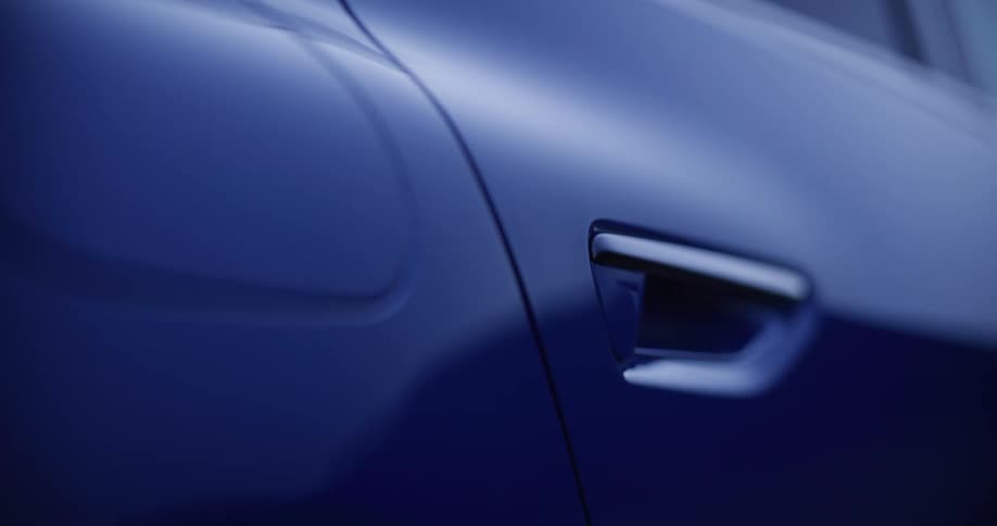 A close-up, slow pan reveals the sleek, aerodynamic lines and flush door handle of a modern blue electric car