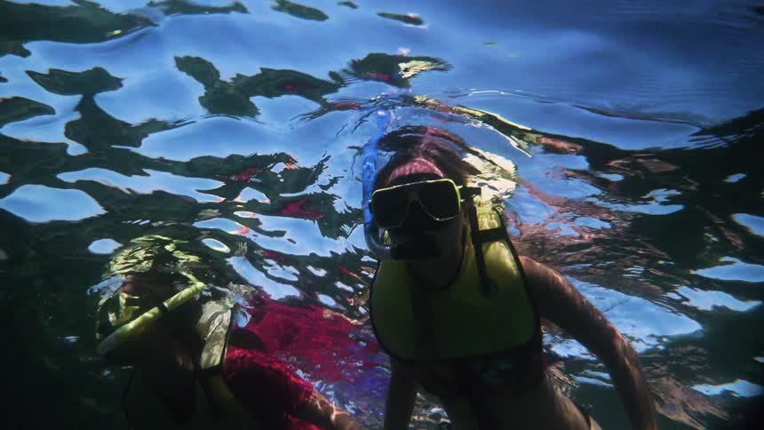 A couple of women floating and snorkeling in water