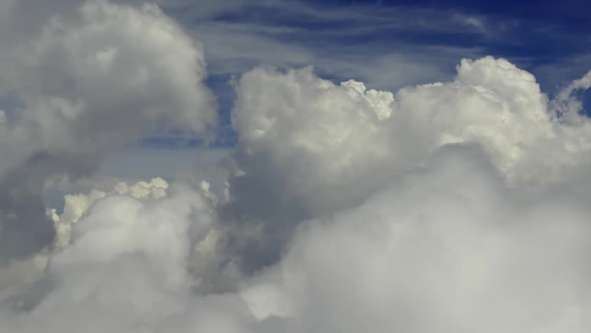 A serene aerial journey flies through a sea of fluffy white clouds against a deep blue sky