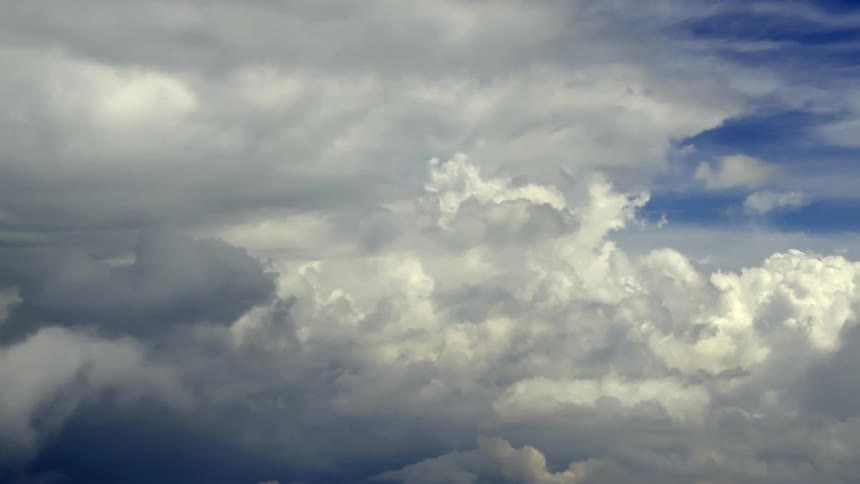 Flying through a vast and dynamic cloudscape of soft white and grey clouds drifting across the sky