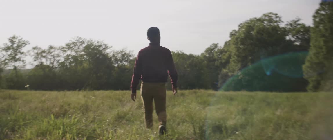 A man is walking through an open field during the day
