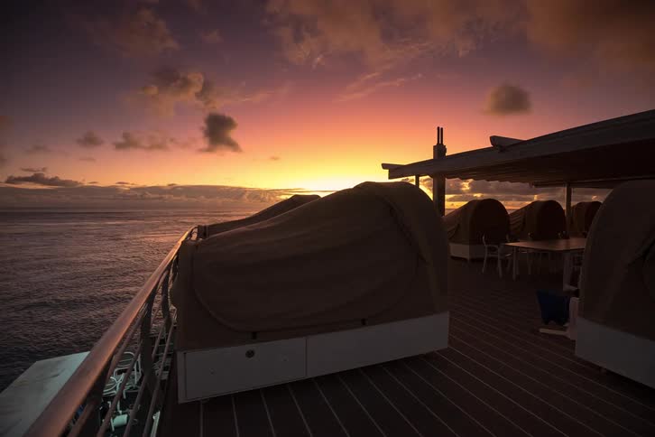 A stunning day-to-night timelapse from the deck of an ocean pontoon shows people preparing for bed as the sun sets in a blaze of color over the water