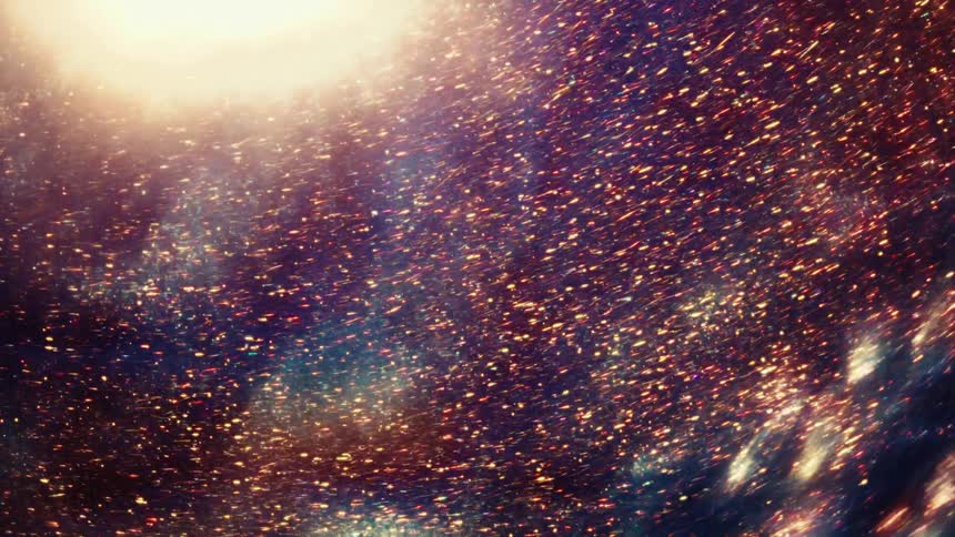 A swirling galaxy of golden dust particles illuminated by a bright celestial light