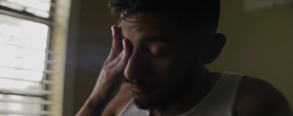 Man in a white tank top sitting up in bed