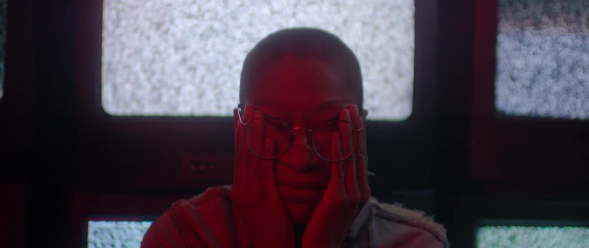 A person rubs their face in front of TV's full of static