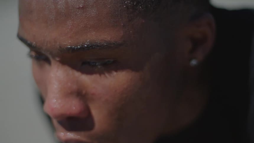 A slow motion extreme close-up reveals the intense focus and determination on a young athlete's sweaty face