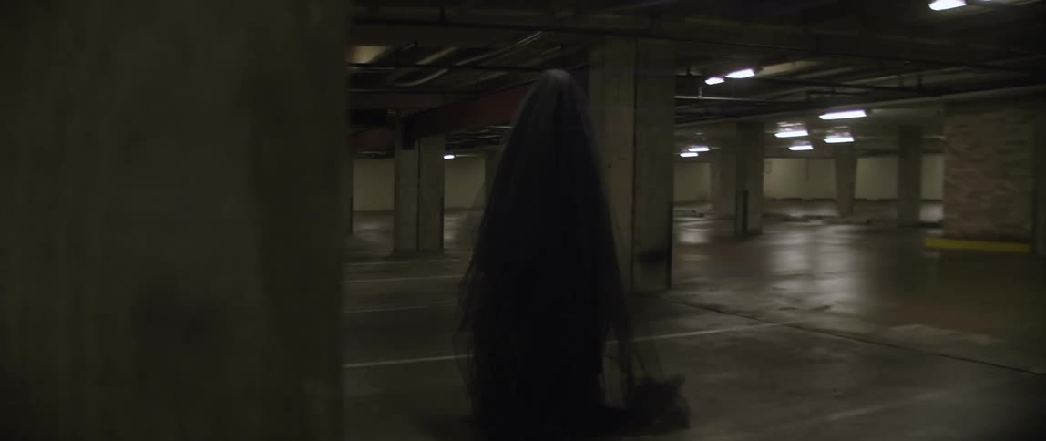 A robed figure moves in a parking lot
