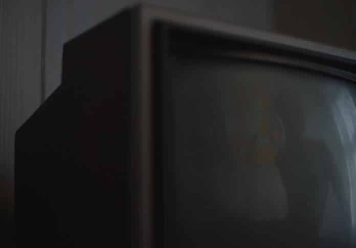 A close up of a retro television reflecting a dark and blurry room
