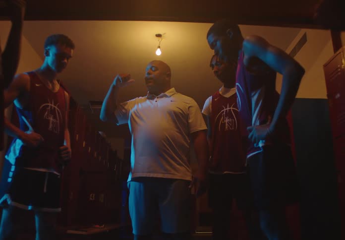 Low angle dolly in on a coach giving an intense and motivational speech to his basketball team in a dark locker room