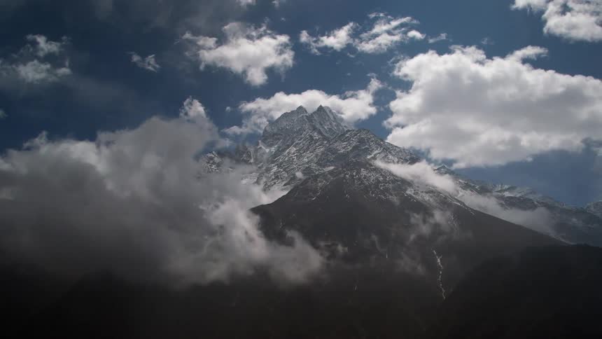 Time lapse view of clouds rolling over snow tipped mountains