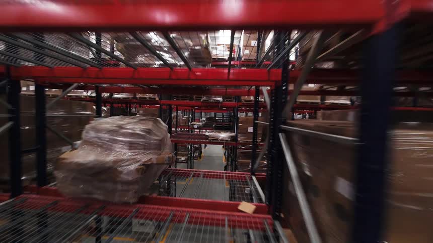 An immersive drone flight through the towering shelves and narrow aisles of a massive industrial warehouse