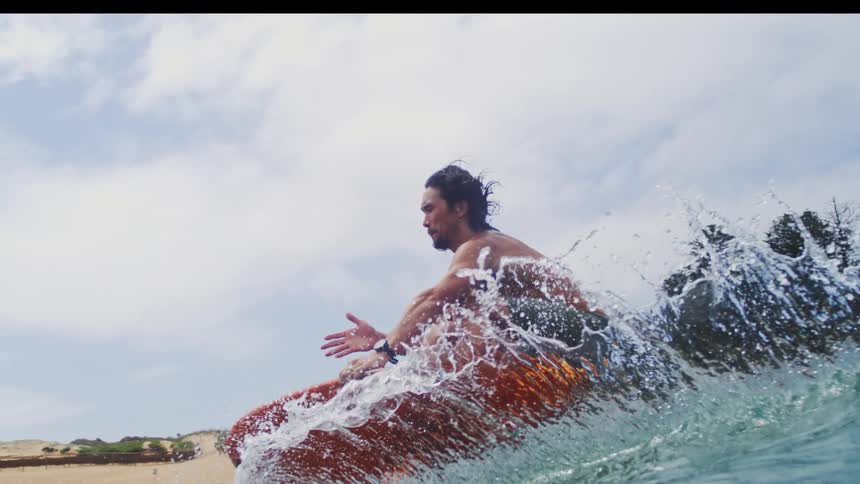 An athletic man gracefully rides an electric hydrofoil surfboard on a wave in stunning slow motion
