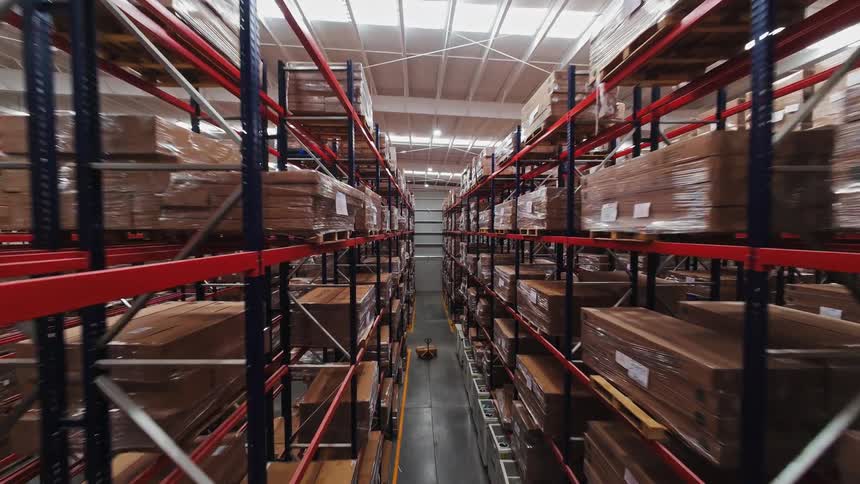 Smooth camera movement through a large, well-organized warehouse with towering racks full of boxed merchandise