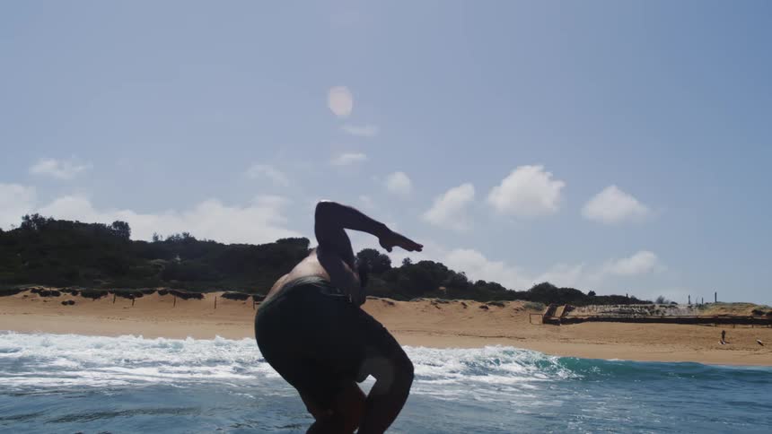 In slow motion, a man skillfully rides a hydrofoil surfboard above the ocean waves before losing his balance and falling into the water